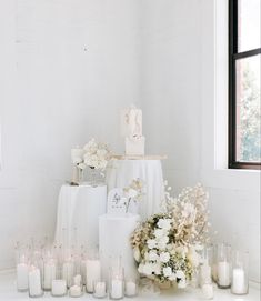 a table topped with lots of white flowers and candles