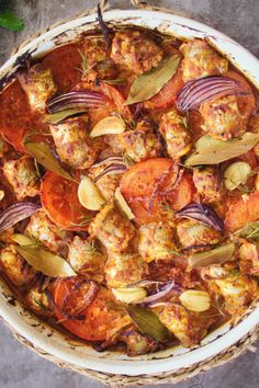 an overhead view of a dish with meat, tomatoes and onions in it on a table