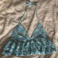 a crocheted halter top laying on a white bed with a blue string