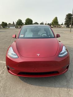 a red tesla parked in a parking lot