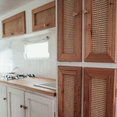 a kitchen with white cabinets and wood paneling on the walls, along with a sink