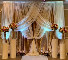 a wedding ceremony setup with gold sequins and white draping on the wall