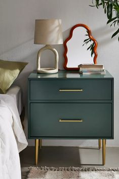 a nightstand with a mirror on it next to a bed