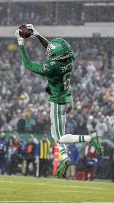 a football player jumping in the air to catch a ball with his hands and feet