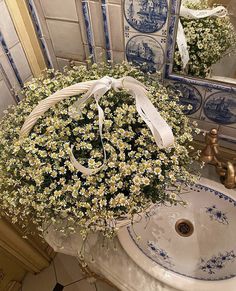 a basket filled with daisies sitting on top of a sink next to a mirror