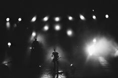 two people standing in front of spotlights on a stage with their backs to the camera