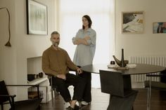 a man and woman are sitting at a table in the middle of a living room