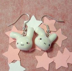 two white bunny shaped earrings sitting on top of pink stars