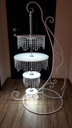 three tiered cake stand with chandelier hanging from it's sides in a room