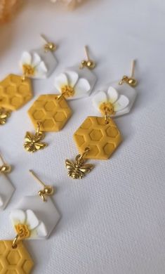 several honeycombs with white and yellow flowers are on a table next to some gold ear pins