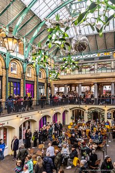 an indoor mall filled with lots of tables and people sitting on the benches in front of them