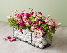 a basket filled with flowers sitting on top of a table next to plates and cups