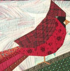 a red bird sitting on top of a quilt