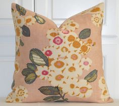 a pink pillow with flowers on it sitting in front of a white door and wooden paneling