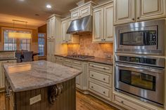 a large kitchen with stainless steel appliances and marble counter tops, along with hardwood floors