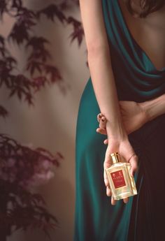 a woman in a green dress holding a bottle of perfume