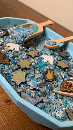 a blue bowl filled with lots of different types of buttons and wooden spoons on top of a table