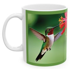 a hummingbird flying towards a flower on a green and white coffee mug with the image of a hummingbird in flight