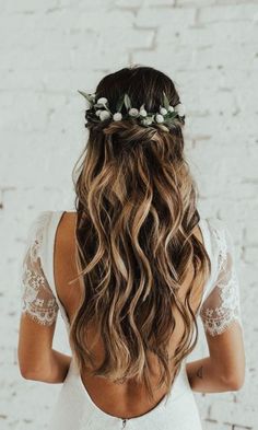 the back of a woman's head with long hair and flowers in her hair