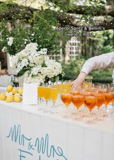 a man standing at a table filled with glasses of orange juice and lemonades