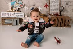 a baby boy sitting on the floor with his toy airplane