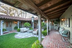 an outdoor patio with seating and potted plants in the back yard, surrounded by brick pavers