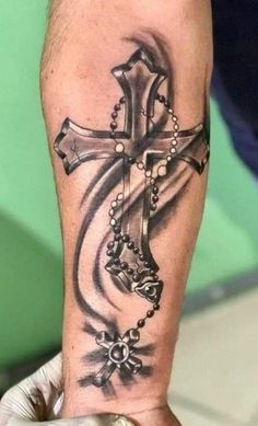 a man's arm with a cross tattoo on the wrist and rosarys around it