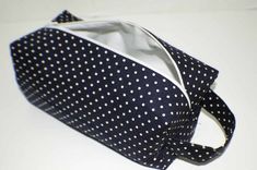 a black and white polka dot purse on a white table with the bottom half open