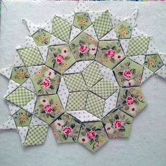 a green and white patchwork piece with flowers on it's center is shown