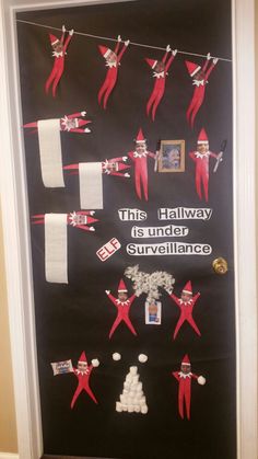 the door is decorated with red and white elfs hanging from clothes line, which reads this hallway is under surveillance