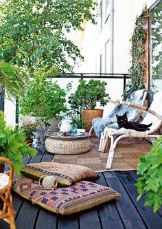 an outdoor patio with wicker furniture and potted plants on the floor, along with various greenery