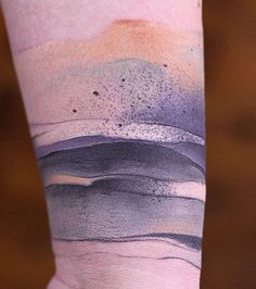 a person with a tattoo on their arm that has an ocean scene painted on it