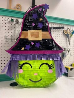 a green bag with purple hair and a witch's hat on top of it