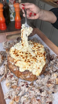 a person is spreading cheese on top of a pizza with other food items around them