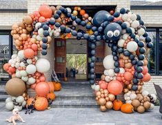 an elephant made out of balloons sitting in front of a building with a dog laying on the ground