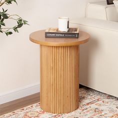 a wooden table with a book and cup on it next to a white couch in a living room