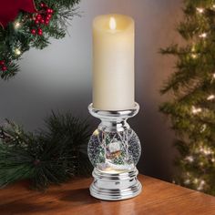 a lit candle sitting on top of a wooden table next to a christmas wreath and tree