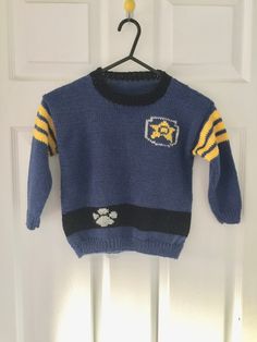 a blue sweater with yellow and black stripes hanging on a door handle, next to a white door