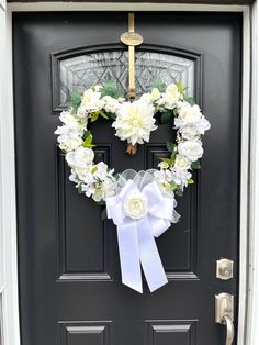 a black door with a wreath and white flowers on it