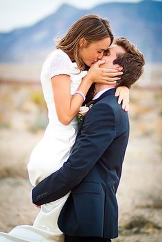 a bride and groom kissing in the desert