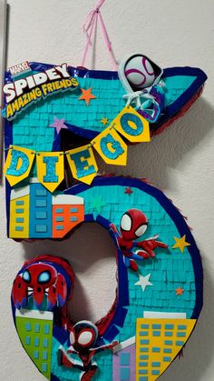 the number five is made out of paper and has spiderman figures on it, hanging from a wall