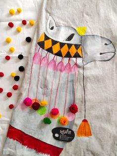 a white shirt with colorful pom poms on it and a dog's head