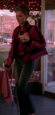 a woman is walking down the sidewalk with her cat in her jacket and boots on