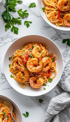 two bowls filled with shrimp pasta and garnished with parsley on the side