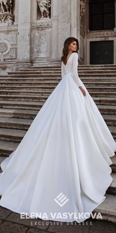 a woman in a white wedding dress standing on some steps with her back to the camera