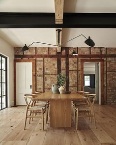 a wooden table surrounded by chairs in a room with exposed brick walls and wood flooring