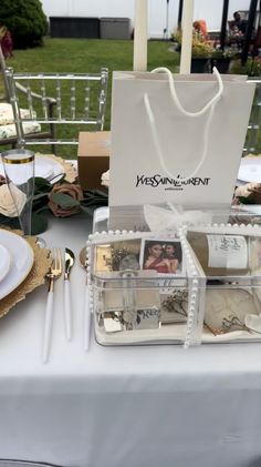 the table is set with white plates, silverware and personalized bags for guests