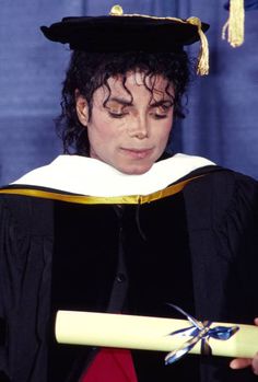 a man in a graduation cap and gown holding a diploma