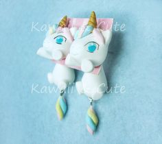 two white unicorns with blue eyes are hanging from a necklace on a blue background