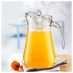 a glass pitcher filled with orange juice on top of a table